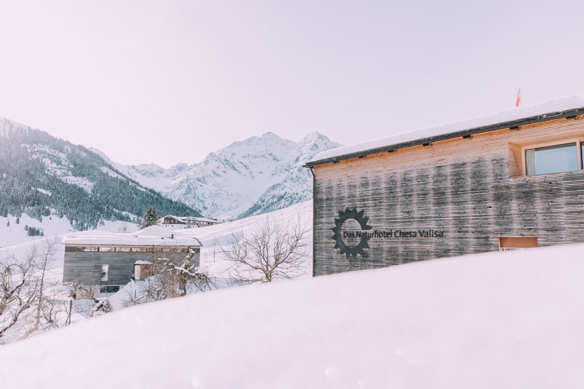 Haus Chesa fotografiert über Schneeberg, im Hintergrund weiße Berge