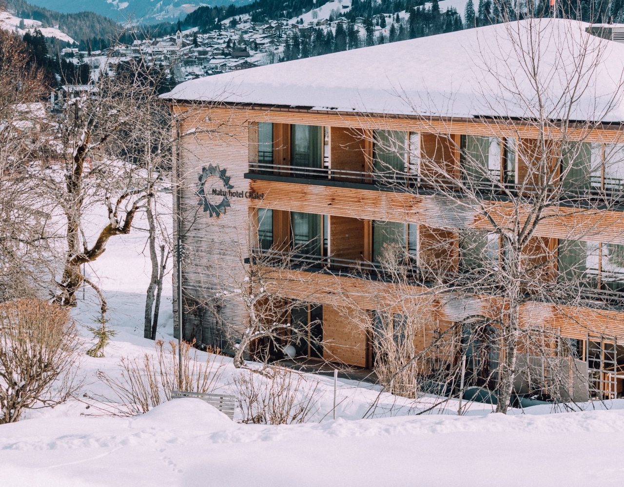 Naturhotel Chalet fotografiert von verschneitem Berg aus