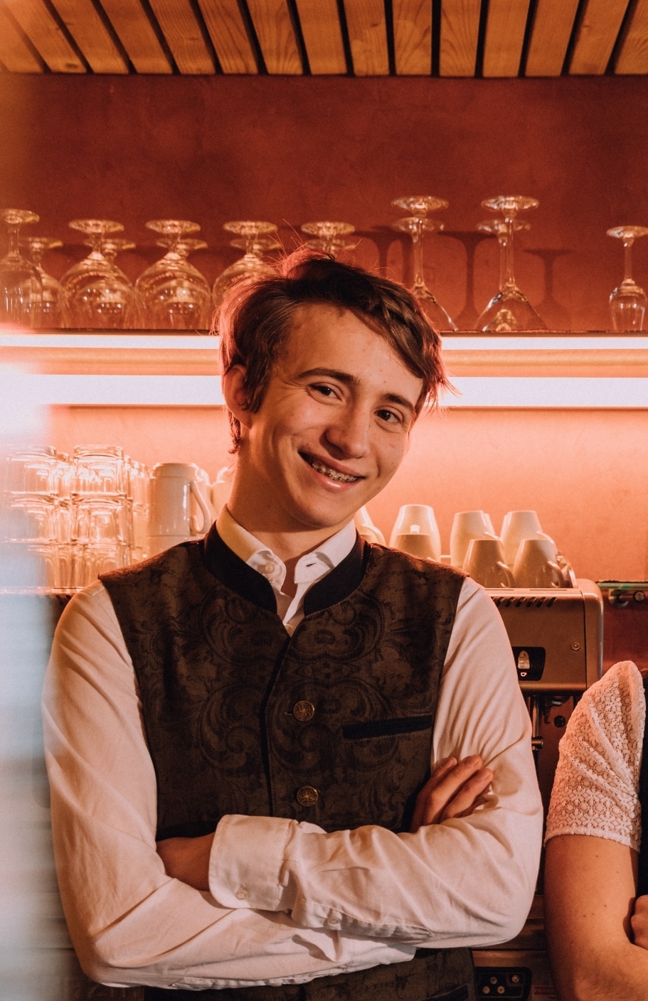 Praktikantin und Praktikant mit verschränkten Armen hinter der Bar
