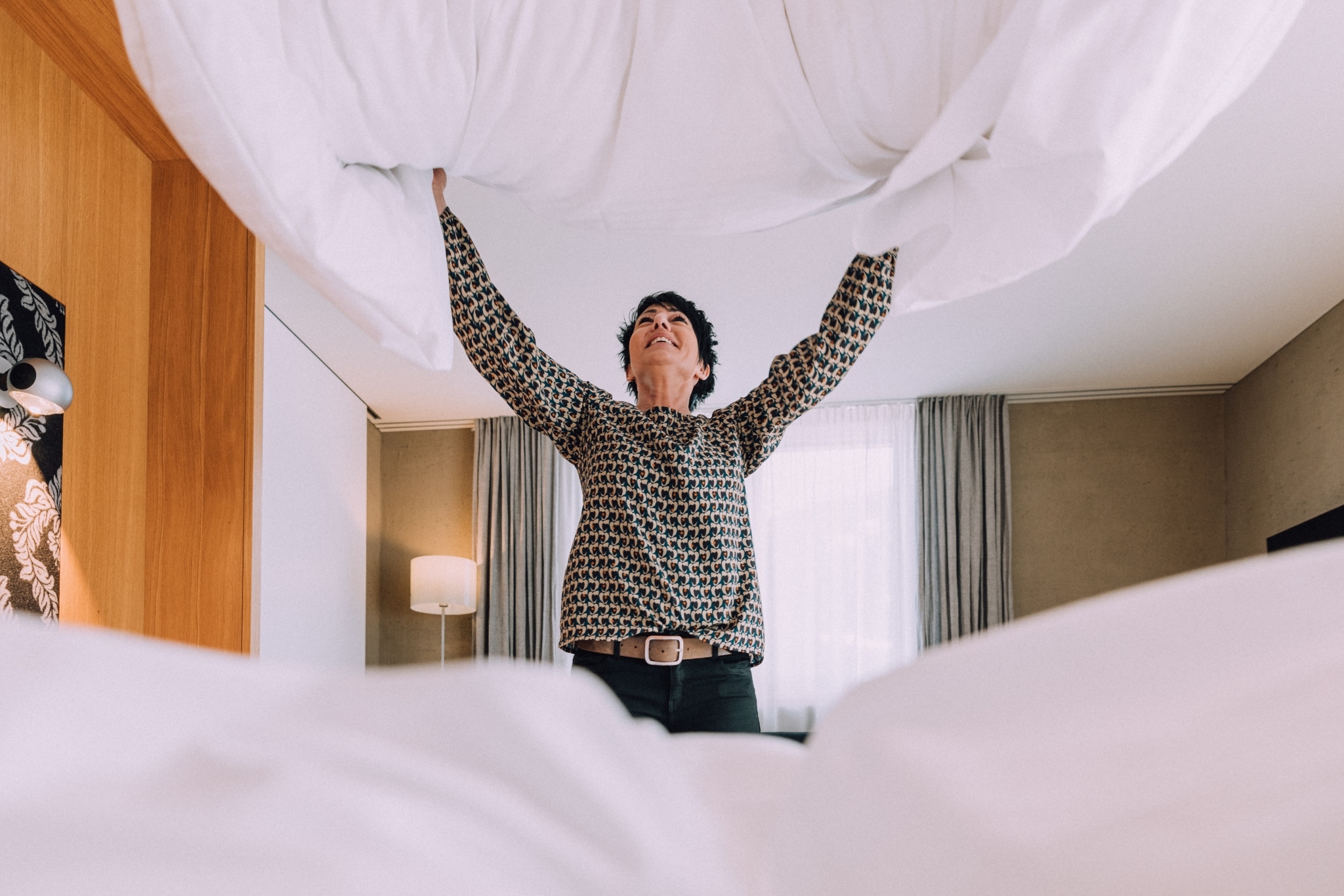 Hausdame schüttelt Bett auf Frau Holle im Hotelzimmer