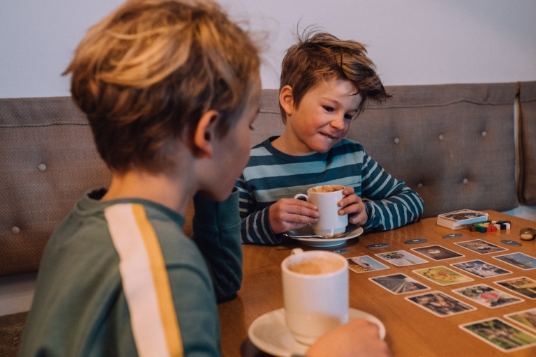 Jungs im Naturhotel trinken Kakao und spielen Karten