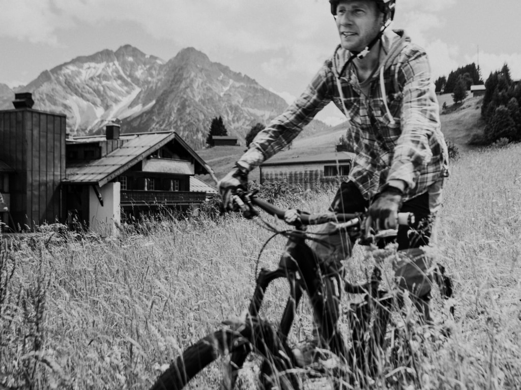 Fahrradfahrer vor Bergen am Naturhotel in Schwarz Weiß