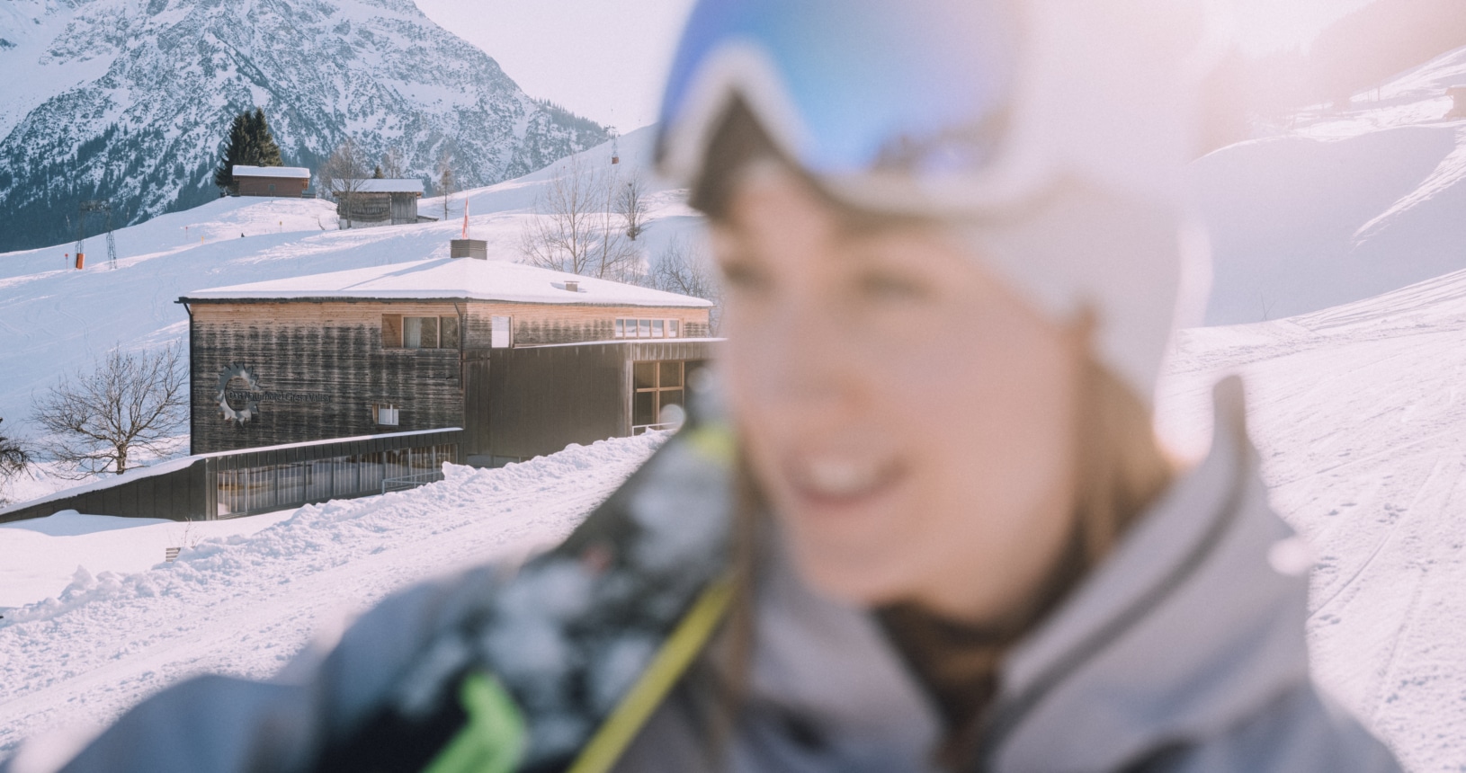 Naturhotel hinter Skifahrerin auf der Piste
