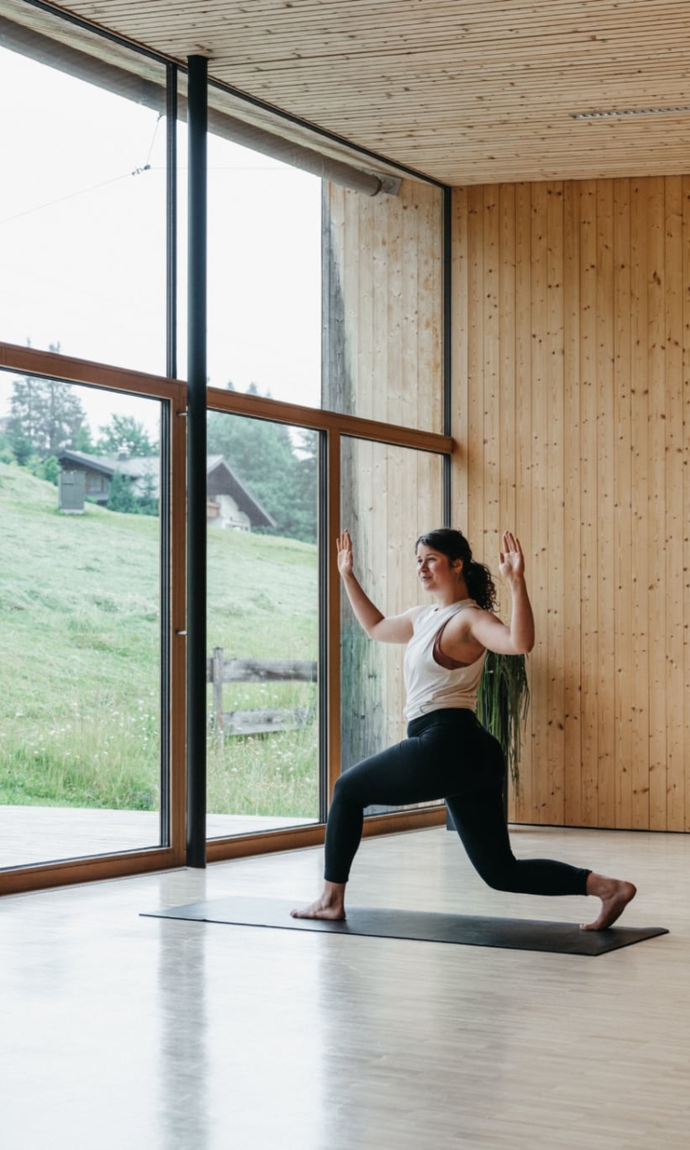 Frau macht Yoga im Seminarraum am Wasser