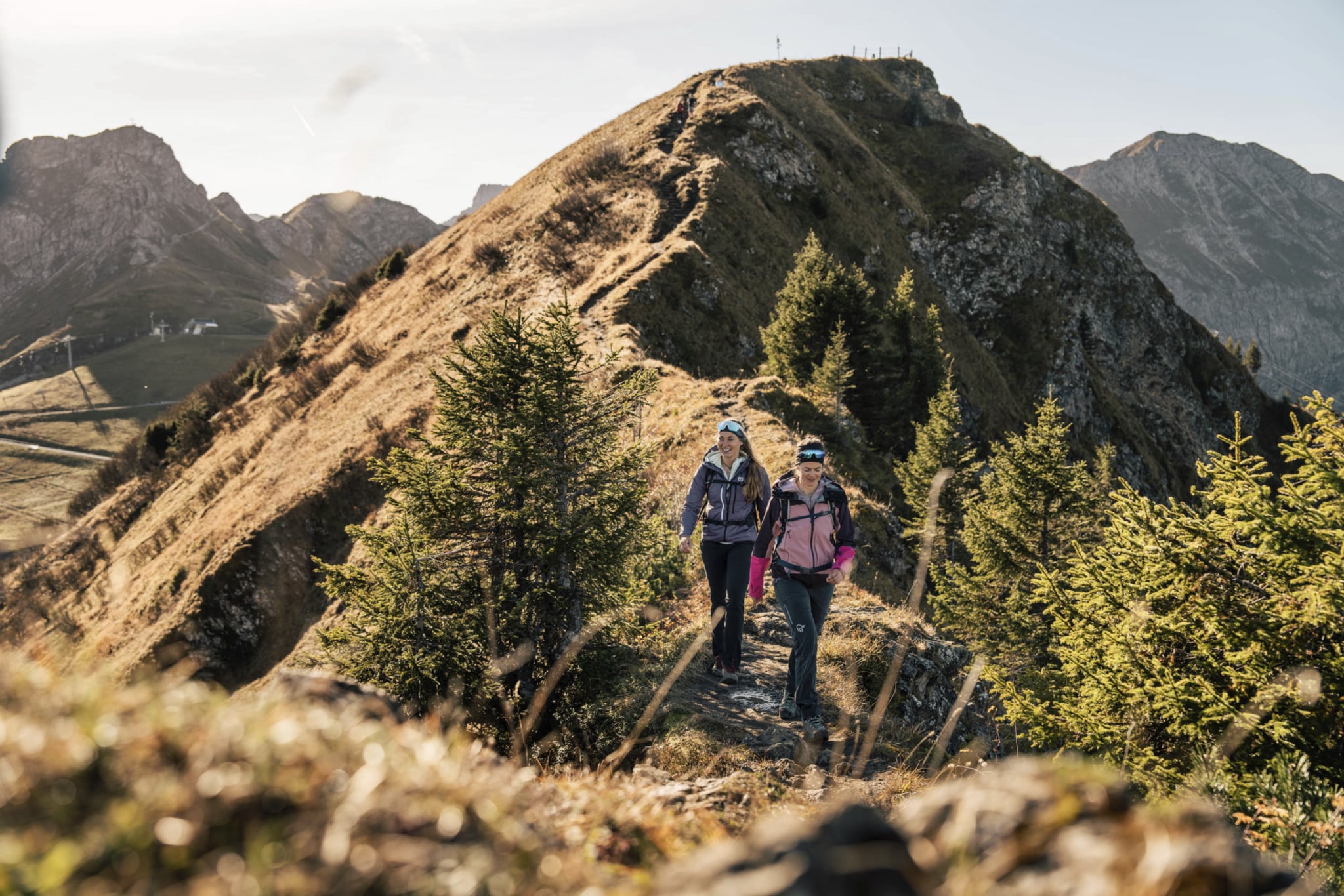 Zwei Frauen beim Wandern im Herbst in den Bergen auf einem Grat