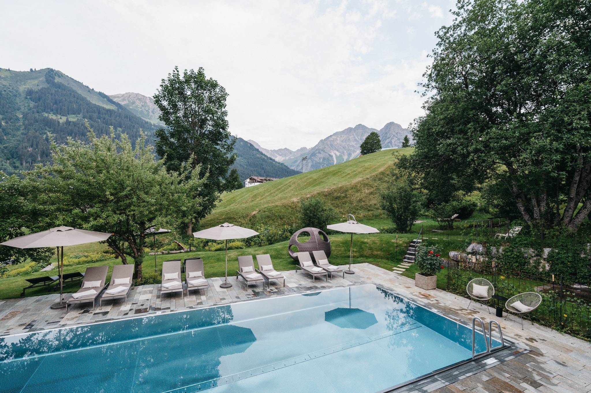 Außenpool mit Sonnenliegen und Blick in die Berge