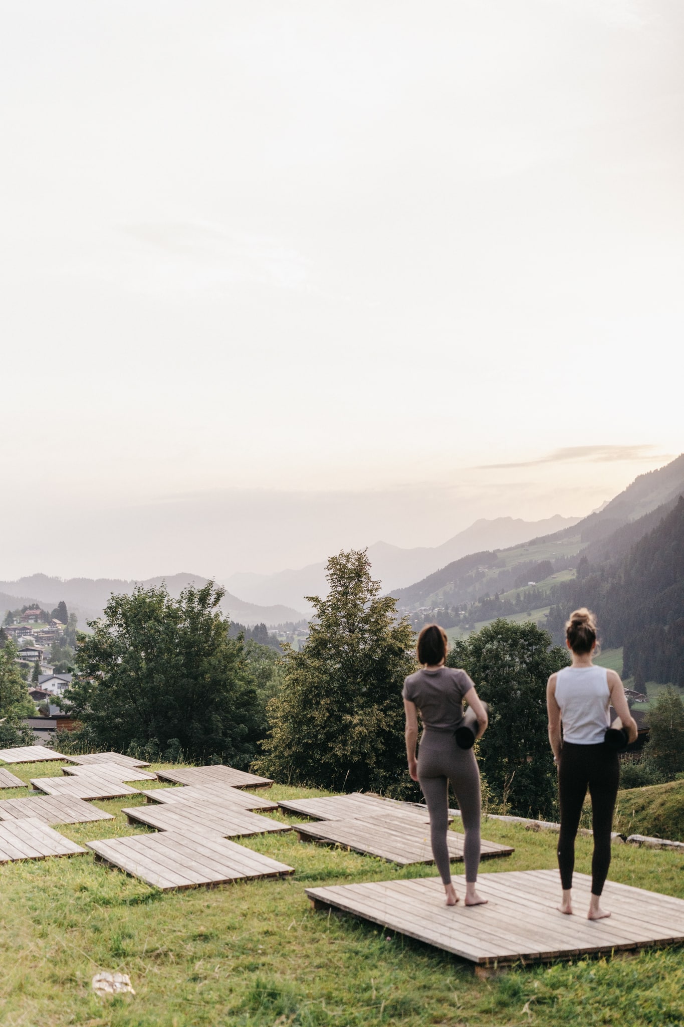 Zwei Frauen stehen mit Yogamatte unter dem Arm bei Morgenstimmung auf den Yogaplattformen