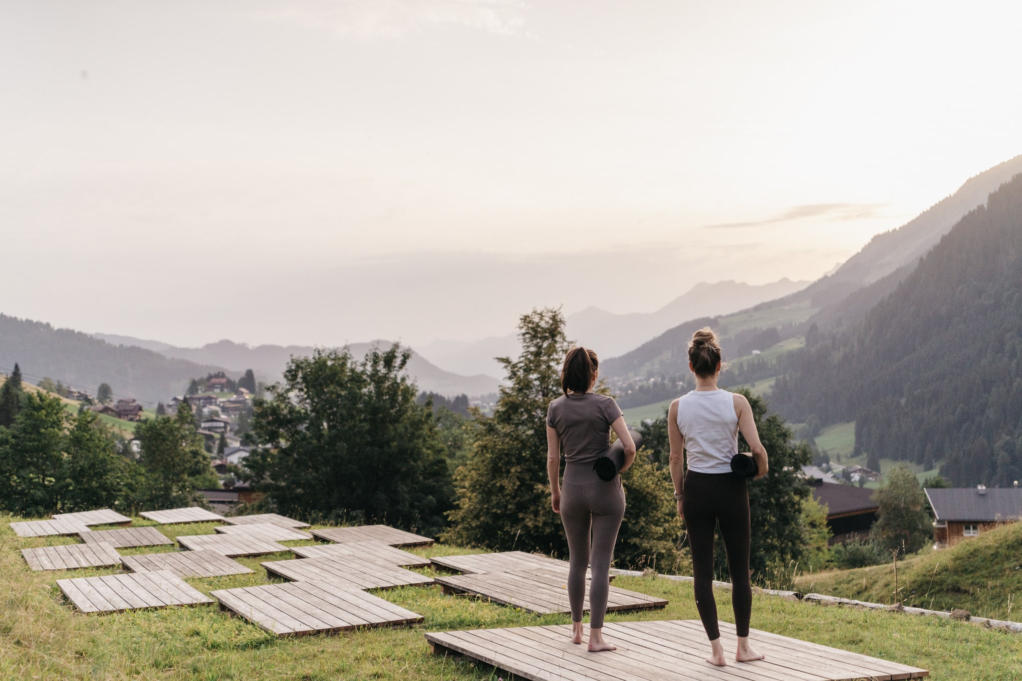 Zwei Frauen stehen mit Yogamatte unter dem Arm bei Morgenstimmung auf den Yogaplattformen